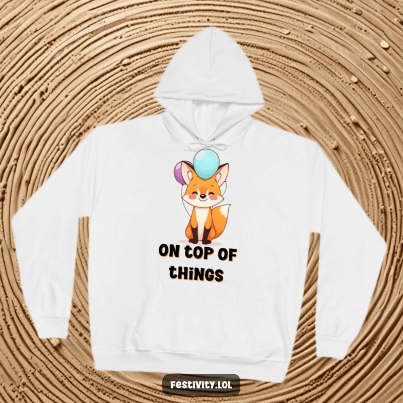 Funny fox hoodie featuring a happy fox with a stack of balloons balanced on its nose, offering warmth and a dose of humor.