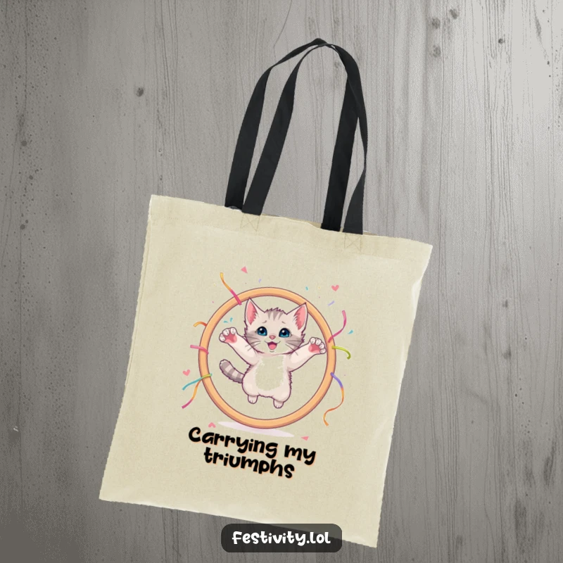 Funny tote bag showing a curious kitten leaping through a giant hoop decorated with streamers.